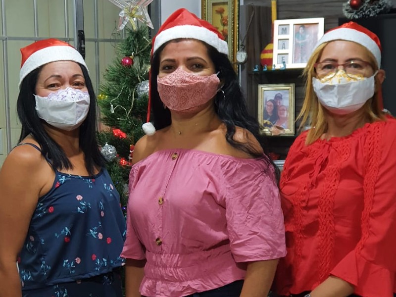 Foto de Rosália com as irmãs Rosilãn e Rosângela no Natal de 2020. Elas estão com gorro de Papai Noel e todas usam máscara